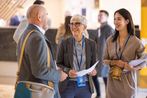 Business people socializing in the lobby of a hotel before a conference event starts A group of well dressed business people socializing in the lobby of a hotel before a conference event starts delegate stock pictures, royalty-free photos & images