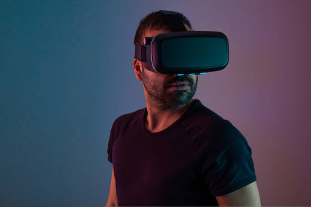 istock Young man in VR glasses headset interact with virtual reality in color neon light, future technology, education video gaming 1438332428