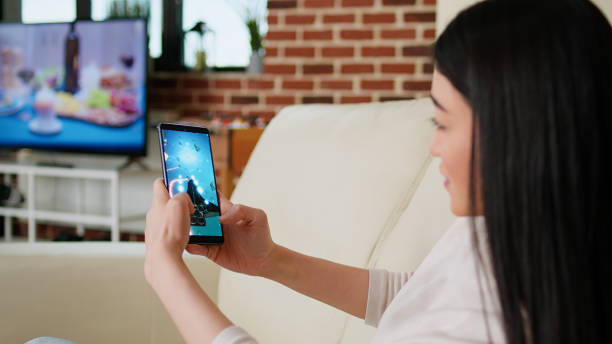 istock Playful asian woman playing space shooter game on smartphone device while working remotely 1438337812