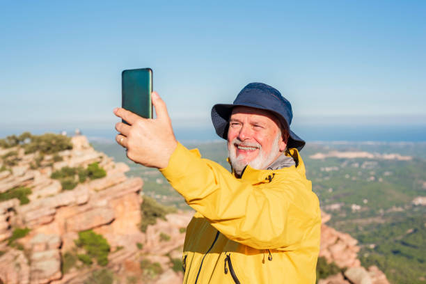 istock happy elderly man using phone to take selfie on the top of summit 1438339199