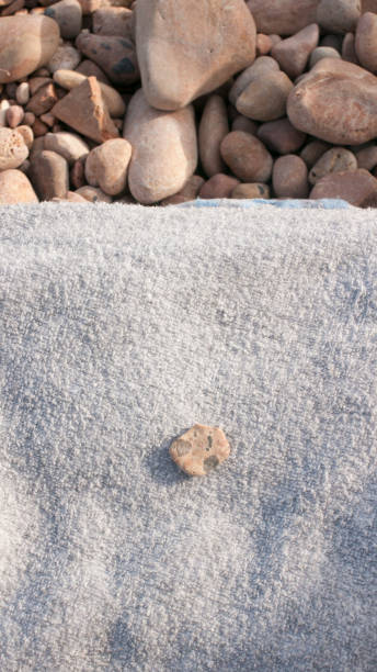 istock Stone on a towel on pebbles ground in a beach 1438341134