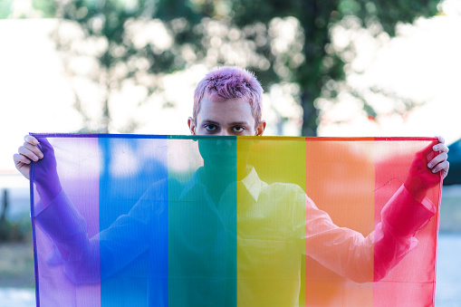 Portrait of  non-binary person waving gender fluid flag