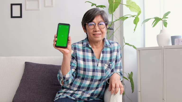 Asian senior woman show green screen smartphone