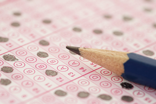 Close-up Of Person's Hand Marking Number On Lottery Ticket With Pen