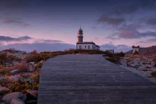 A boardwalk leading to the Larino Lighthouse during the sunset in the evening in Spain