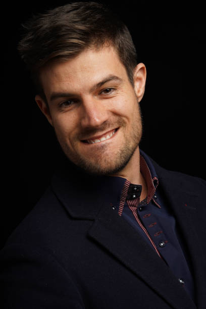istock Attractive young male biting his lip and flirting with someone while standing over black background 1438349793
