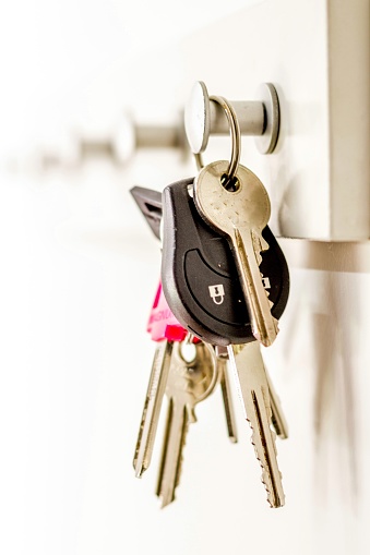 A selective focus vertical shot of a bunch of keys hanging on a key holder with a blurred background