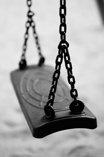 A vertical shot of a swing attached to metal chains