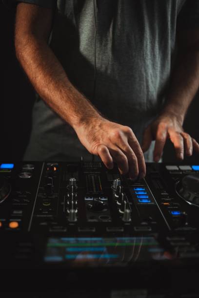 istock Vertical closeup of a DJ working under the lights against a dark background in a studio 1438353135