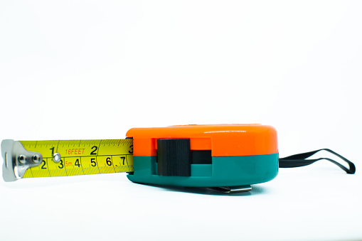 Close-up of a tape measure on a blue defocused background. Shallow depth of field, space for copy.