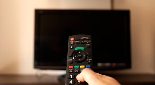 istock TV remote in the foreground with the finger on the buttons 1438353405