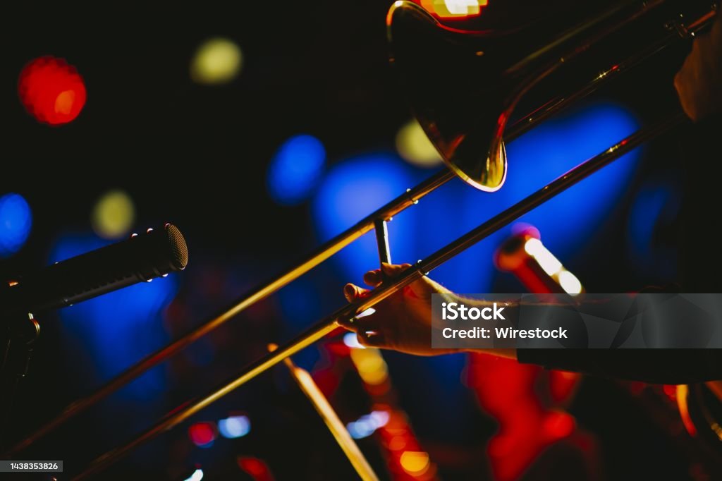 Closeup shot of a person playing the trombone at a concert A closeup shot of a person playing the trombone at a concert Trombone Stock Photo