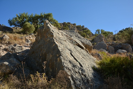 A closeup of a pyramid shaped stone on a rocky slope of a mountain under the sky