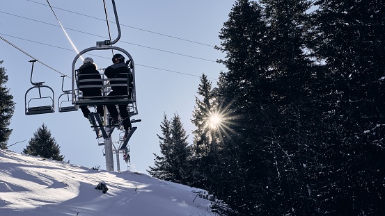 Alpe d'Huez, France – February 28, 2020: A couple sitting on a cable car at Alpe d Huez ski resort with trees and blue sky