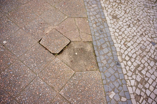 A high angle shot of a cobblestone ground with one missing tile