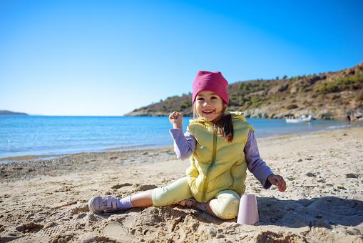 Happy little girl building sandcastle on the beach