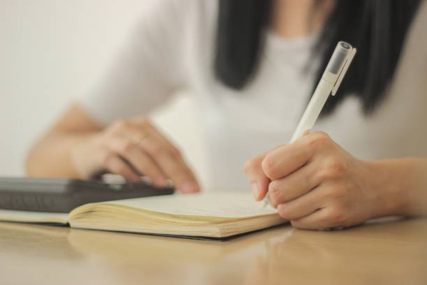 istock Girl writing on her notebook with a white pen 1438354754