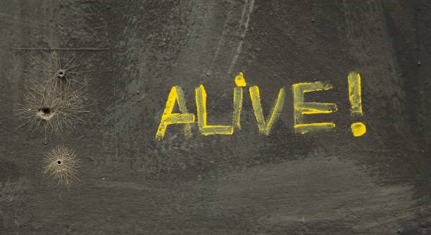 istock Concrete surface with a yellow message Alive with a warning sign on it 1438355413