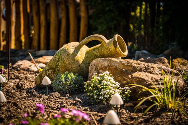 An old clay pot nestled among vibrant green and purple-hued leaves in a flourishing garden setting in Denmark. A serene and harmonious nature scene highlighting rustic and organic elements.