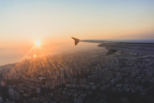 A beautiful shot of an airplane wing over a cityscape in Antalya, Turkey with the bright sun in the background