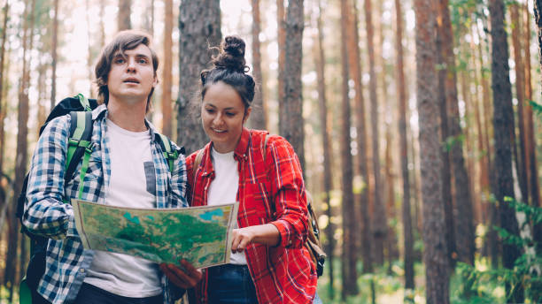 istock Lost tourists are standing in forest looking at map, talking and gesturing to finding way . People, travelling and beautiful nature concept 1438357072