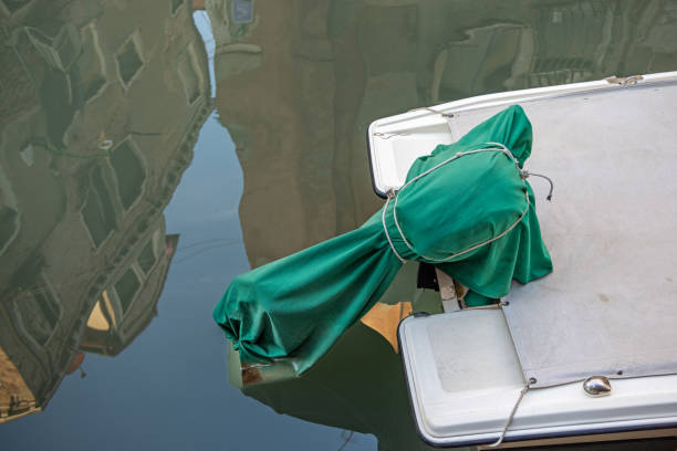 Outboard motor under a green tarpaulin and reflection of palaces in the water in a narrow canal in Venice