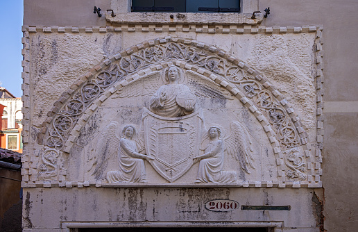 Venice, Italy - October 7th 2022:  Old religious marble relief on a wall of a residential building in the center of the old and famous Italian city Venice
