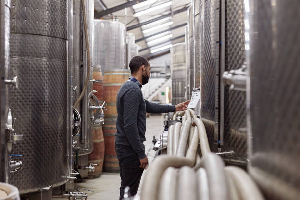 istock Wine, production and covid with a black man at work in a cellar for fermentation in the winery industry. Factory, manufacturing and plant with a male worker busy in an alcohol produce distillery 1438359590