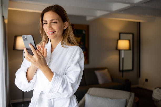 istock Beautiful woman using mobile beauty apps holding smartphone in bathrobe 1438361464