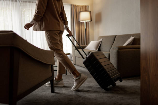istock Elegant dressed woman entering hotel suite and pulling suitcase 1438361505