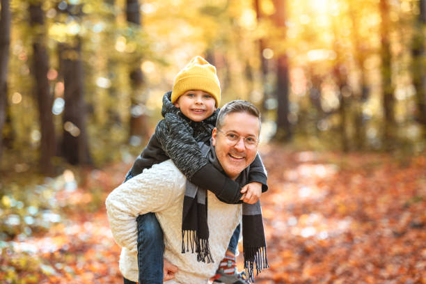 hombres felices con hijo adoptado en la temporada de otoño - pareja acogido al aire libre fotografías e imágenes de stock