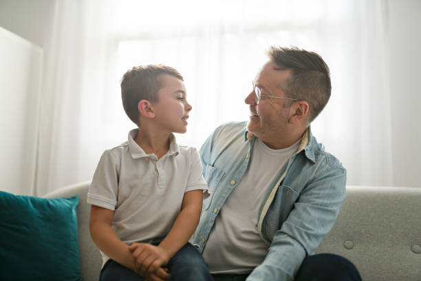istock Happy men with adopted child sit on sofa 1438363666