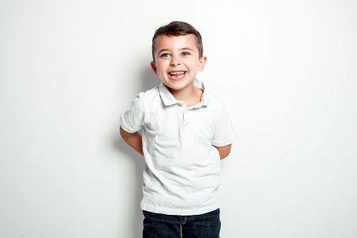 A five year old boy posing over white studio background