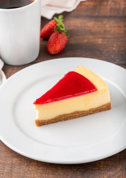 Delicious strawberry cheesecake with coffee next to it on wooden table stock photo