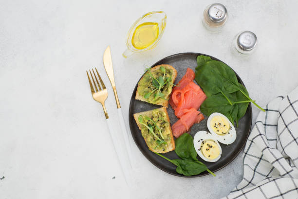 istock A healthy breakfast with two sandwiches with avocado, boiled egg and salmon on a gray background. Top view. 1438369076
