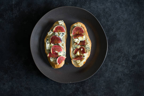 bruschetta with blue cheese and fresh figs on dark background. bruschetta with blue cheese and fresh figs on dark background. plate fig blue cheese cheese stock pictures, royalty-free photos & images