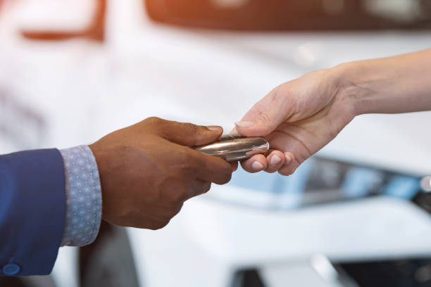 istock Salesman and female customer shake hands and pass car key 1438370554