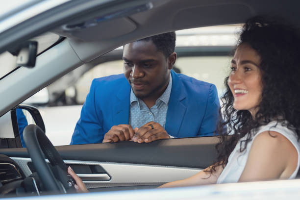 istock Black salesman describes car characteristics to lady client 1438370561