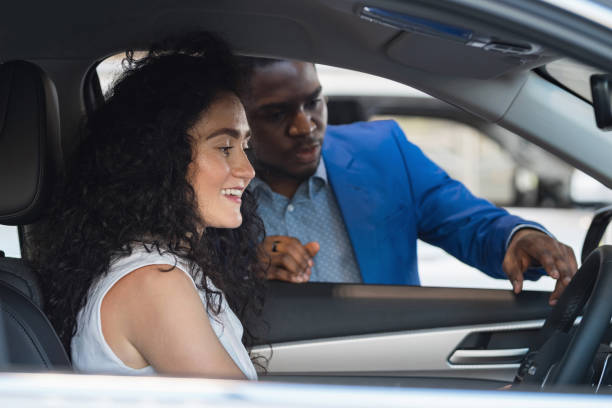 istock Black salesman describes car characteristics to lady client 1438370569