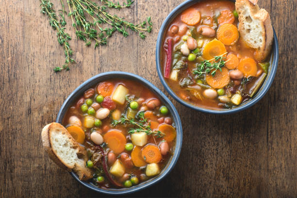 구운 빵과 허브 조각이있는 나무 질감의 배경에 minestrone 야채 수프. 간단한 채식주의 자 소박한 이탈리아 요리, 이탈리아 요리의 고전, 맛있는 건강한 지중해 식 점심 식사 - minestrone 뉴스 사진 이미지