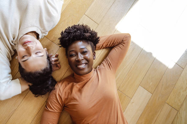istock Two young women lying head to head on the floor 1438372401
