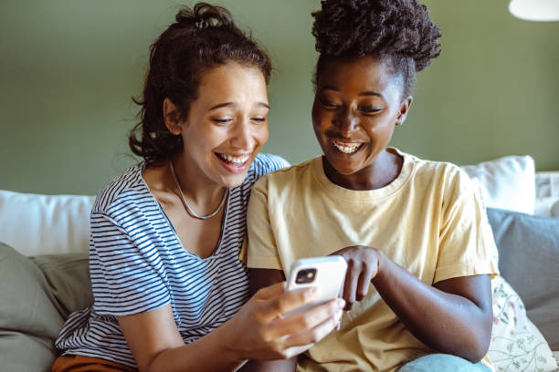 Two young women use smart phones at home stock photo