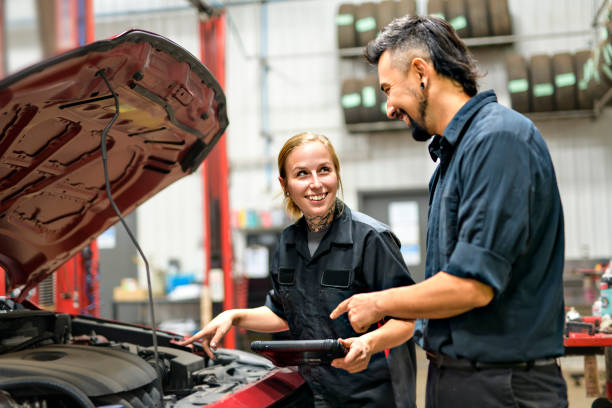 제복을 입은 두 명의 잘생긴 정비공 노동자가 태블릿으로 자동차에서 일하고 있다 - women repairing wrench business 뉴스 사진 이미지