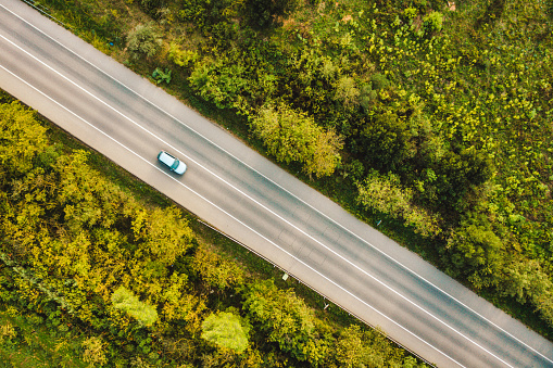 Aerial view of  cars  along a road flanked by a green forest
