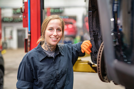 A Handsome mechanic job woman in uniform working on car