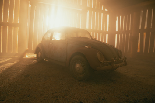 Beaconsfield, UK - November 1, 2022: An old and dusty VW Beetle sits neglected in an old wooden barn. Scale model photography.