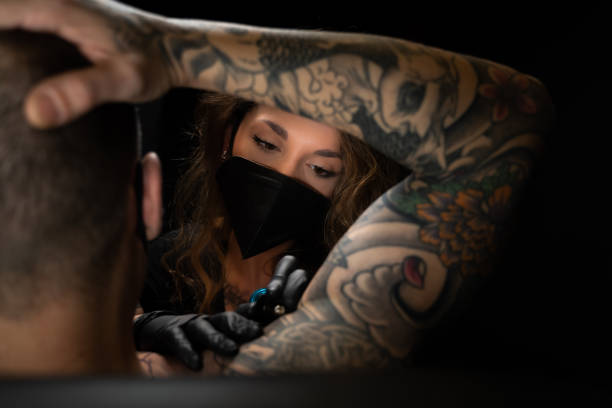 Tattoo artist tattooing a man in a studio stock photo