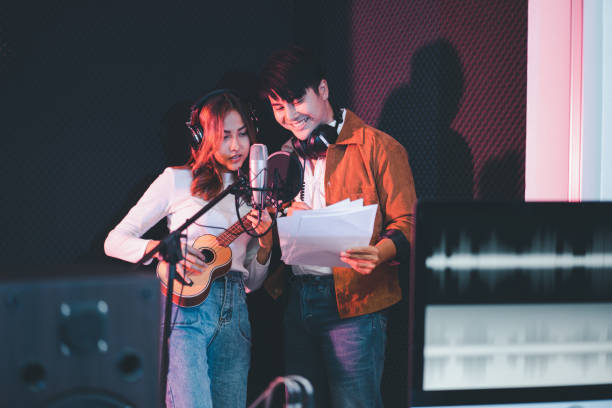 istock Asian couple singers in a recording studio using a studio microphone with passion in music recording studio 1438381846