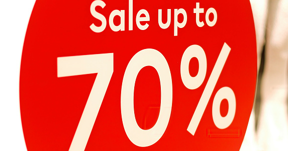 Sale sign at entrance in store. Red round sign with white words, promotion in modern shopping mall. Seasonal discount offer in store. Discounts and black Friday concept. Christmas sell