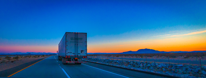 Las Vegas, United States - February 22 , 2013 : A truck driving in the desert during the evening night while the sunset over the desert from las vegas to los angeles